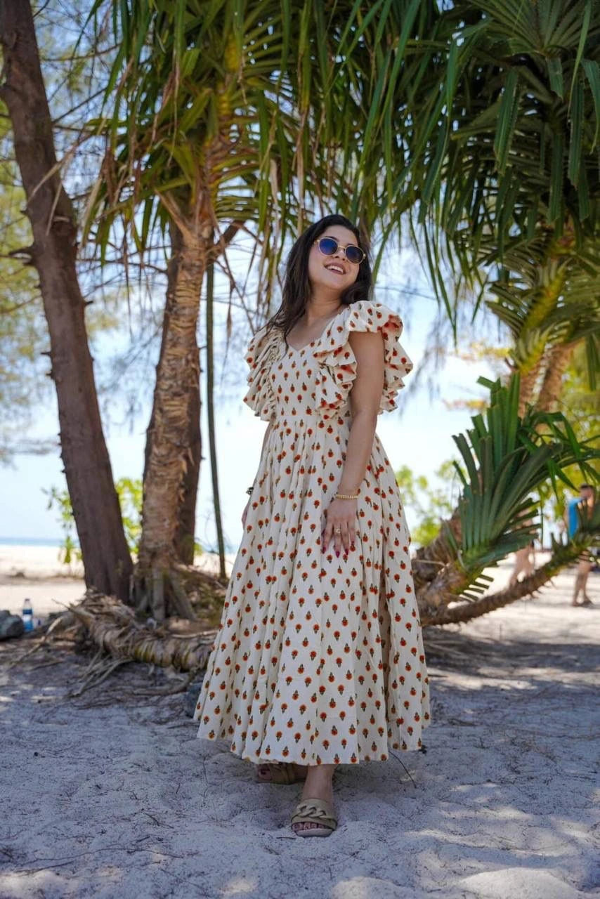 Woman in a polka dot dress standing on a sandy beach with palm trees in the background