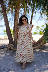 Woman in a polka dot dress standing on a sandy beach with palm trees in the background