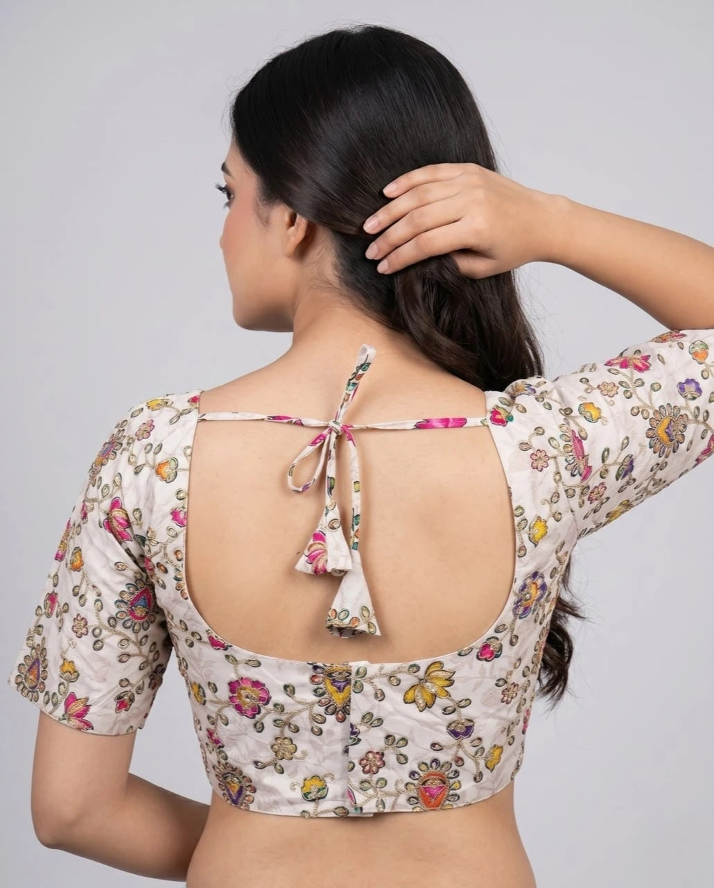 Woman wearing a floral blouse with a backless design on a gray background