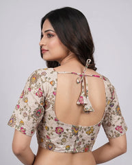 Woman wearing a floral blouse with an open back design on a plain background