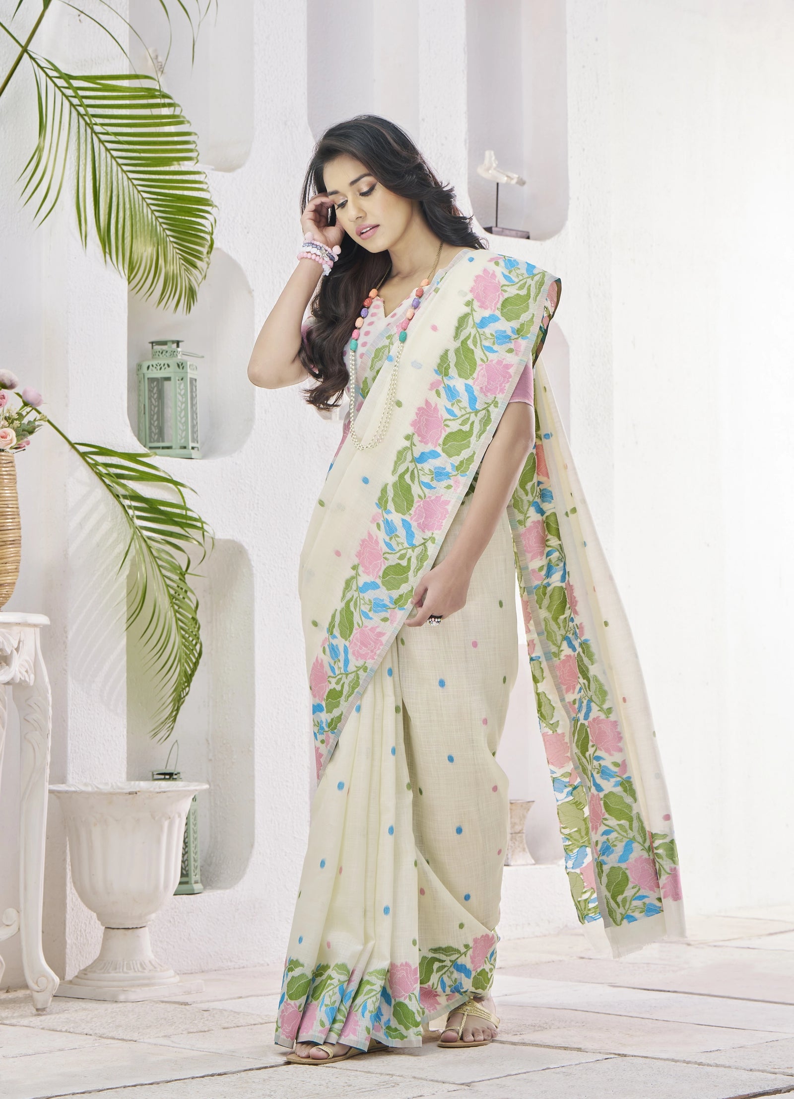 Woman wearing a floral saree in a bright room with plants