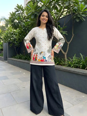 Woman wearing a traditional outfit with a patterned top and black pants, standing outdoors.