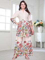 Woman wearing a floral outfit in a bright room with white walls and a vase of flowers.
