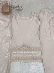 Light gray traditional outfit with intricate embroidery on a textured surface