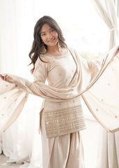Woman in a traditional outfit with a beige dupatta in a bright setting