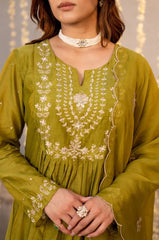 Green embroidered dress with white details worn by a person, against a neutral background.
