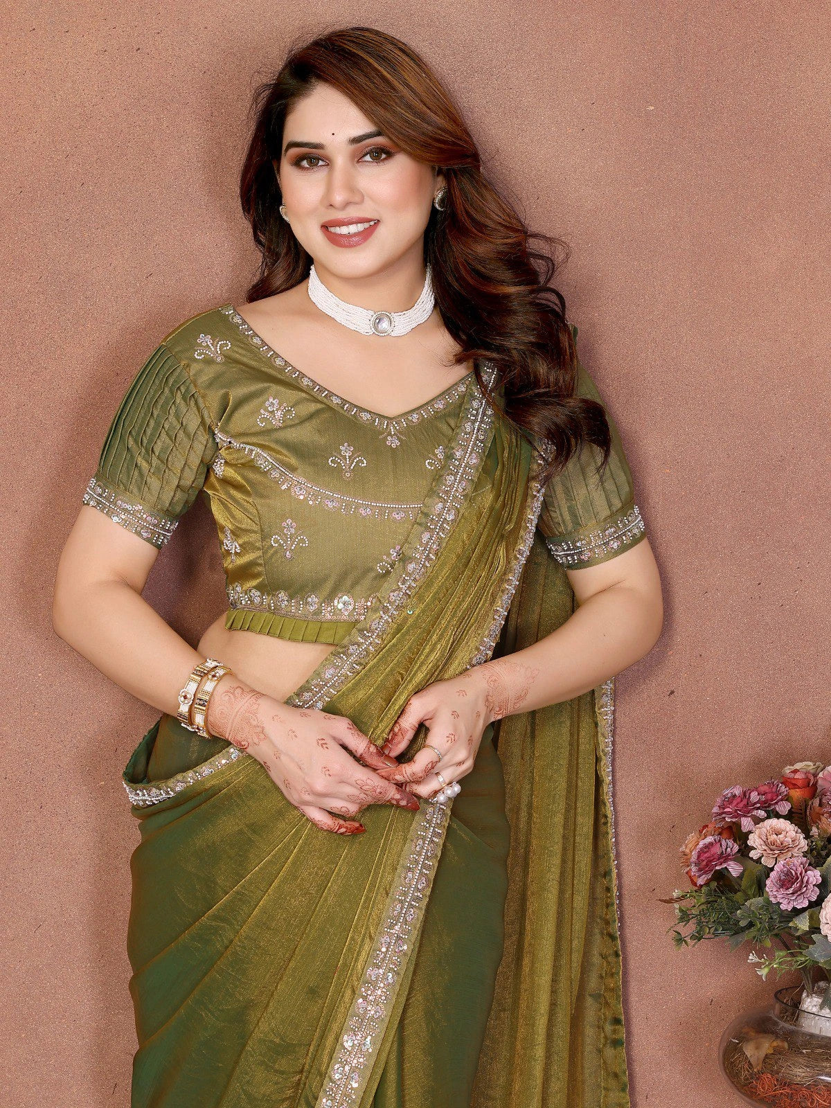 Woman in a green saree with floral decorations in the background