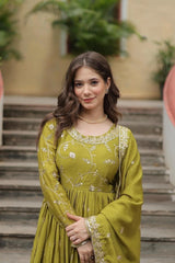 Woman in a green traditional outfit standing outdoors with plants in the background