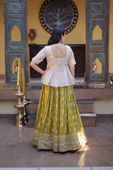 Woman in a traditional outfit standing in a decorative indoor setting.