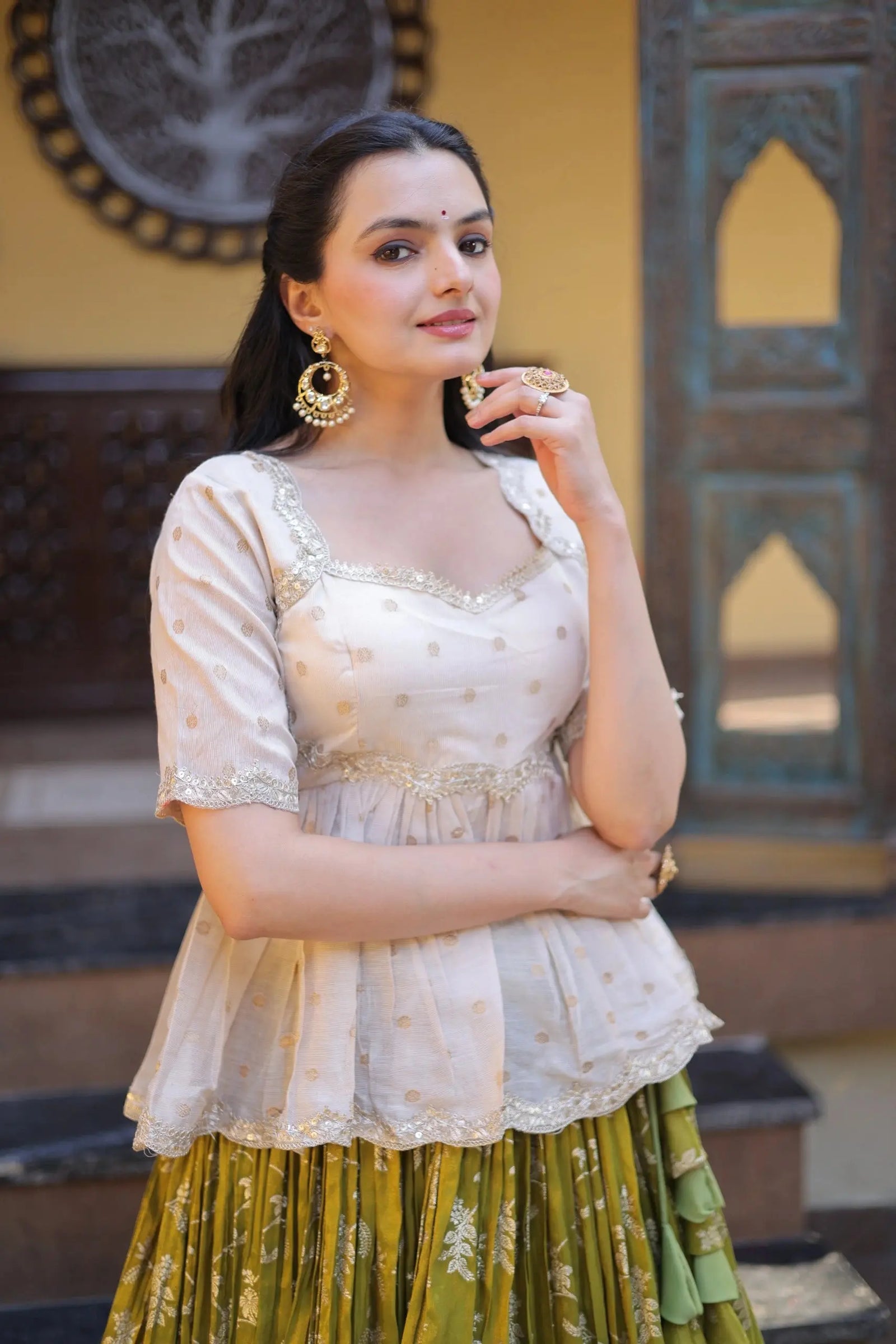 Woman wearing a traditional outfit with a white top and green skirt in an indoor setting.