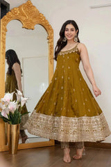Woman in a mustard yellow traditional outfit standing in front of a decorative mirror.
