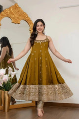 Woman in a green traditional dress standing in front of a decorative mirror.