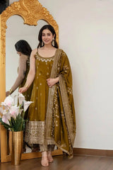 Woman in a traditional outfit standing in front of a decorative mirror with flowers.
