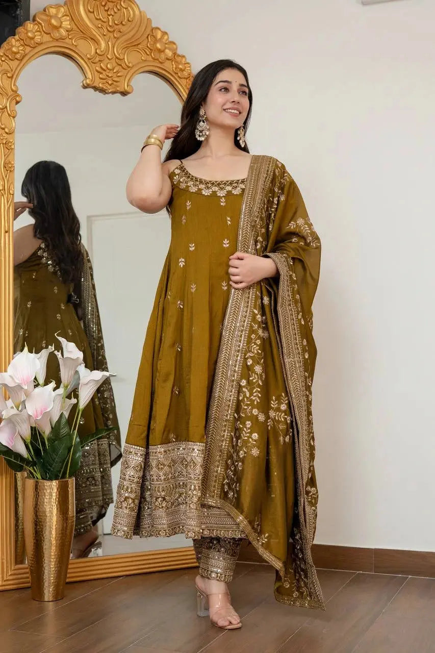 Woman in a green traditional outfit standing in front of a decorative mirror.