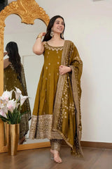 Woman in a green traditional outfit standing in front of a decorative mirror.