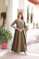 Woman in a traditional outfit standing in an outdoor setting with plants and architectural elements.