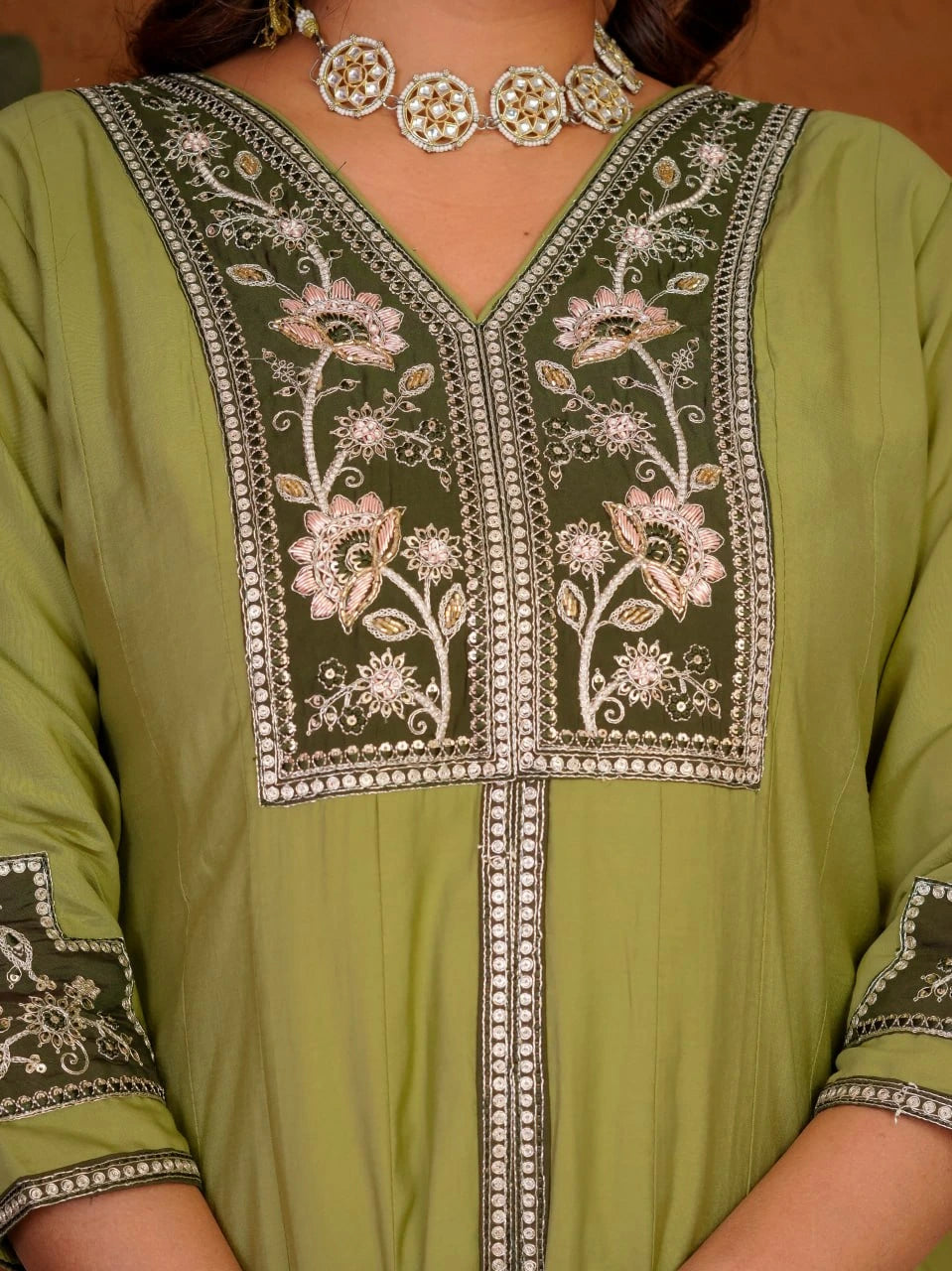 Green embroidered garment with floral patterns on a plain background