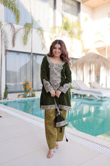 Woman in a green traditional outfit standing by a poolside.