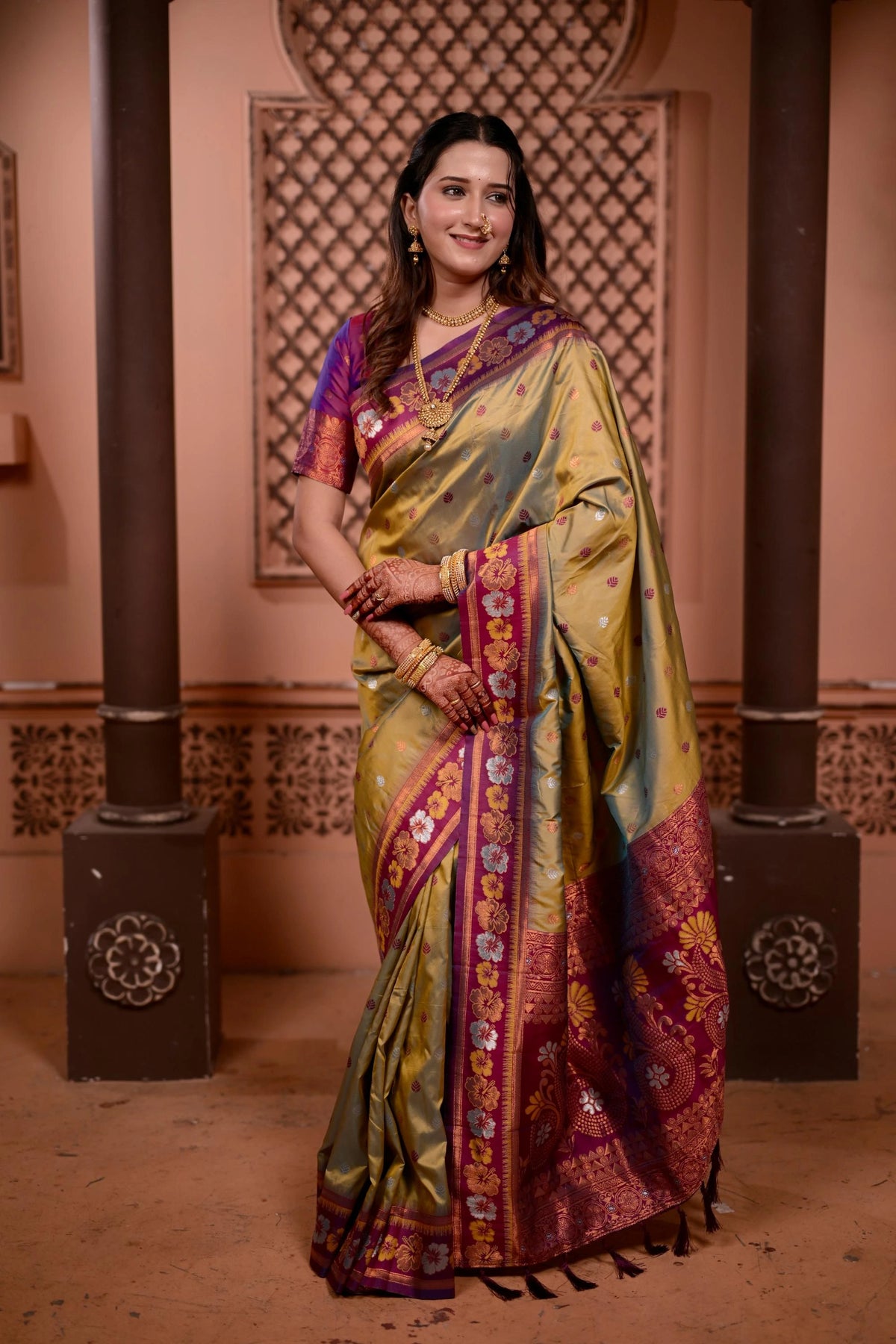 Woman in a traditional saree standing in an ornate indoor setting