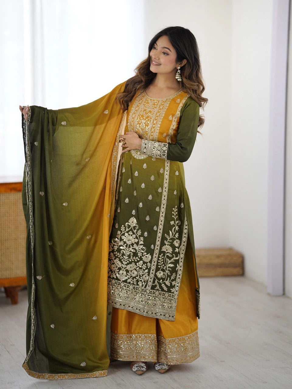 Woman wearing a green and yellow traditional outfit with a sheer dupatta.