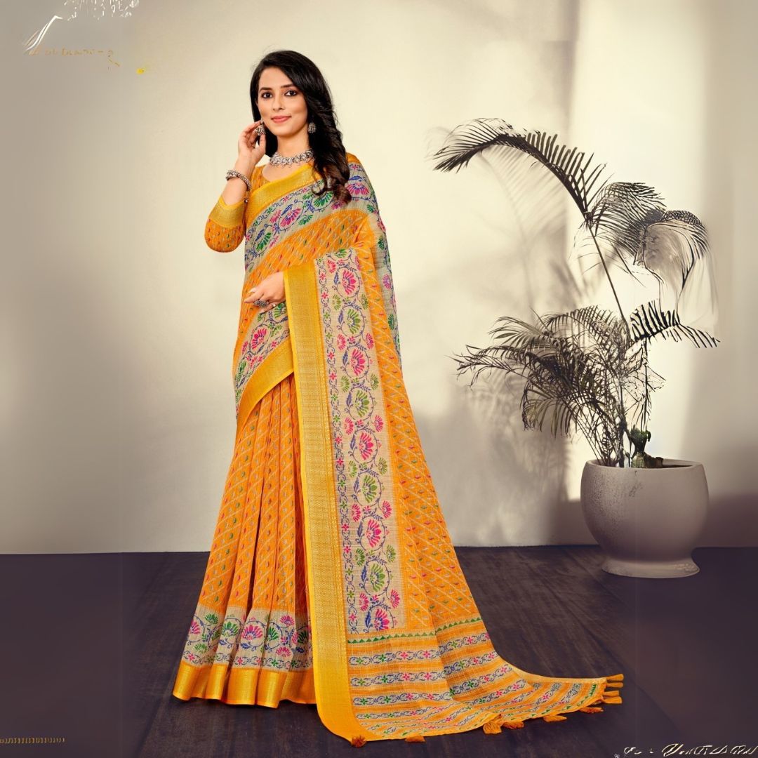 Woman wearing a traditional orange saree with printed patterns in an indoor setting with a potted plant in the background