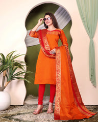 Woman wearing an orange and red traditional outfit with a green curtain and plant in the background