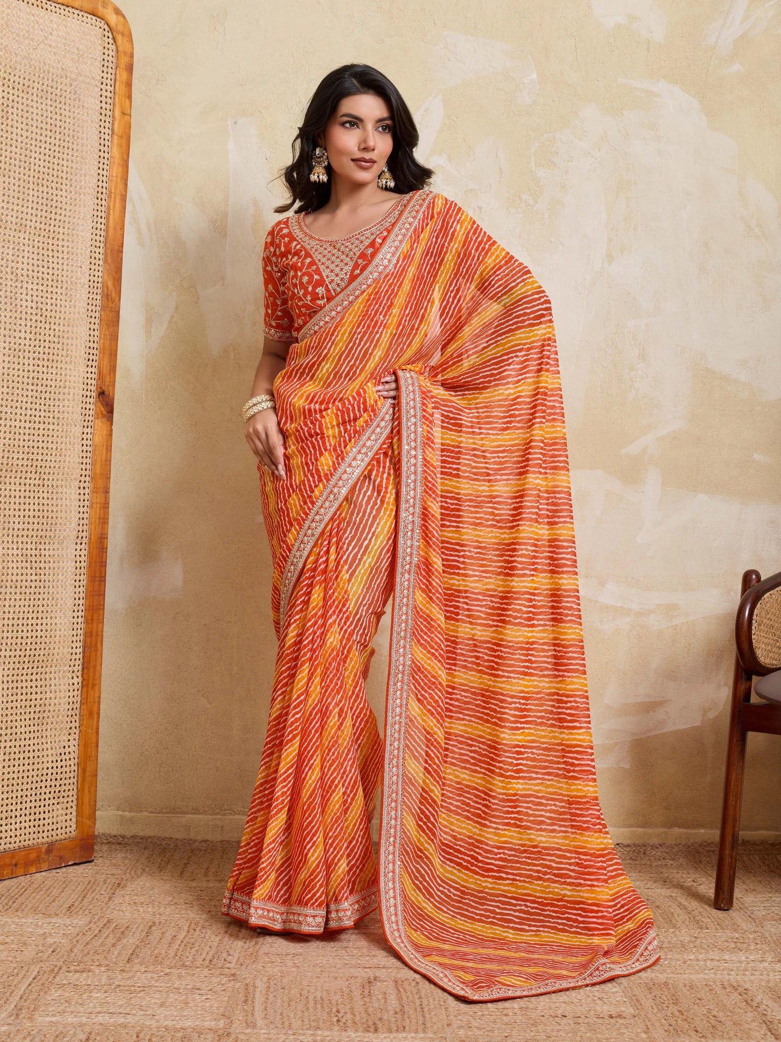 Woman wearing an orange and yellow saree with a neutral background