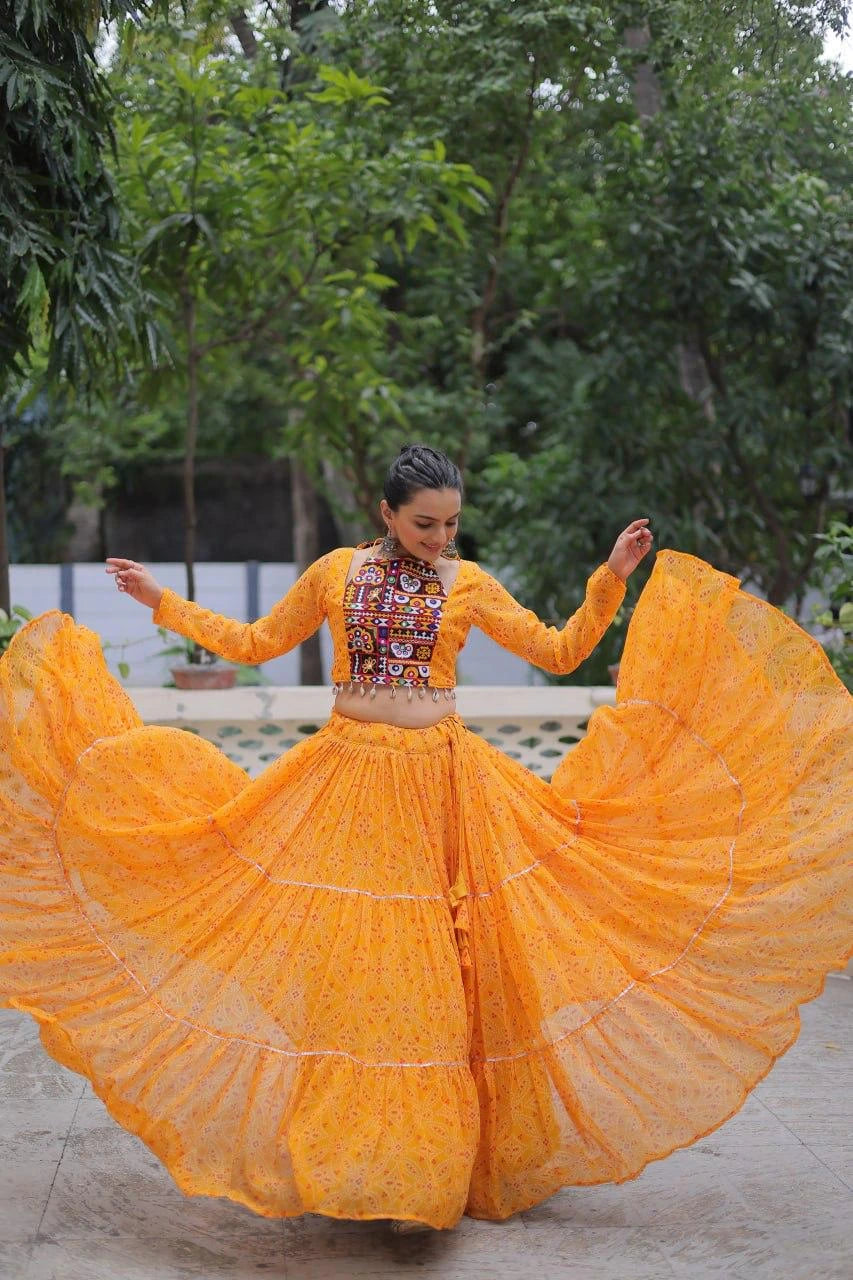 Woman in a bright orange traditional outfit with a colorful top, dancing outdoors.