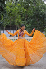 Woman in a bright orange traditional outfit with a colorful top, dancing outdoors.