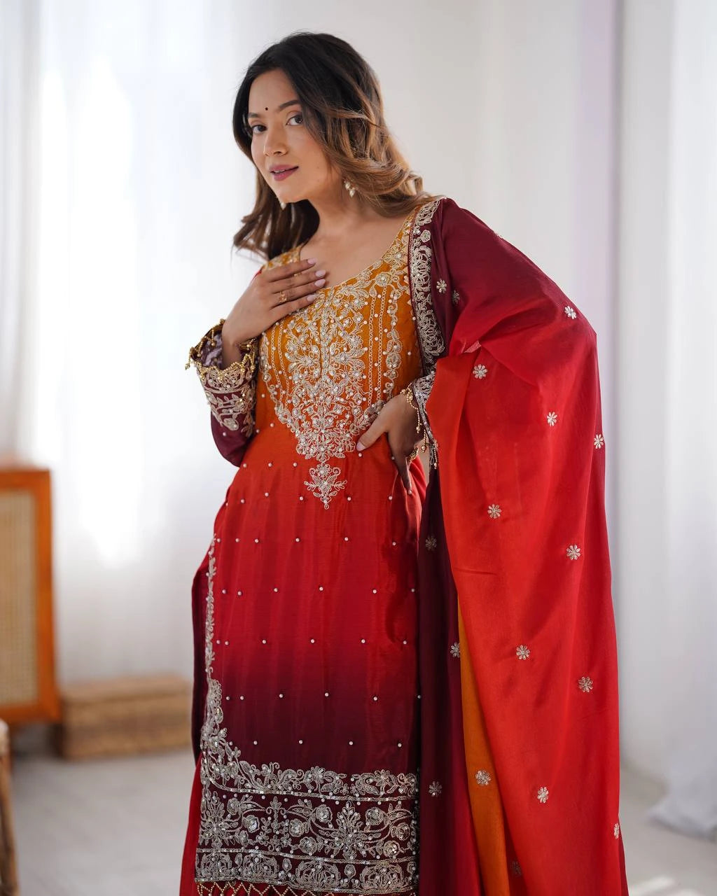 Woman wearing a red and orange traditional outfit with white embroidery against a white background