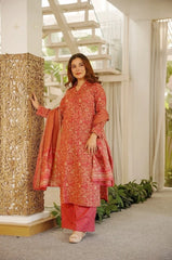 Woman in a red and pink traditional outfit standing next to an ornate column indoors.