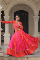 Woman in a vibrant red and pink traditional outfit standing in front of an archway.