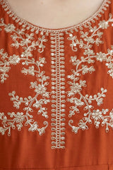 Close-up of a rust-colored fabric with intricate white embroidery