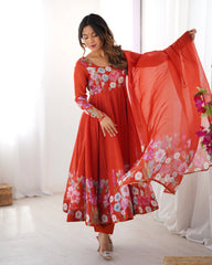Woman wearing a red floral dress holding a matching dupatta in a bright room.