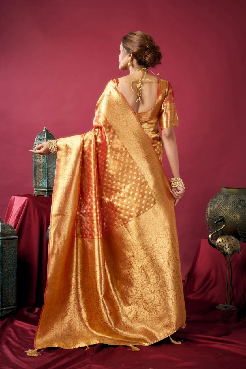Woman in a gold saree standing against a red background