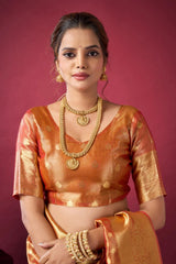 Woman in traditional attire with gold jewelry against a pink background