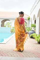 Woman in a yellow saree with a pink blouse standing by a poolside.