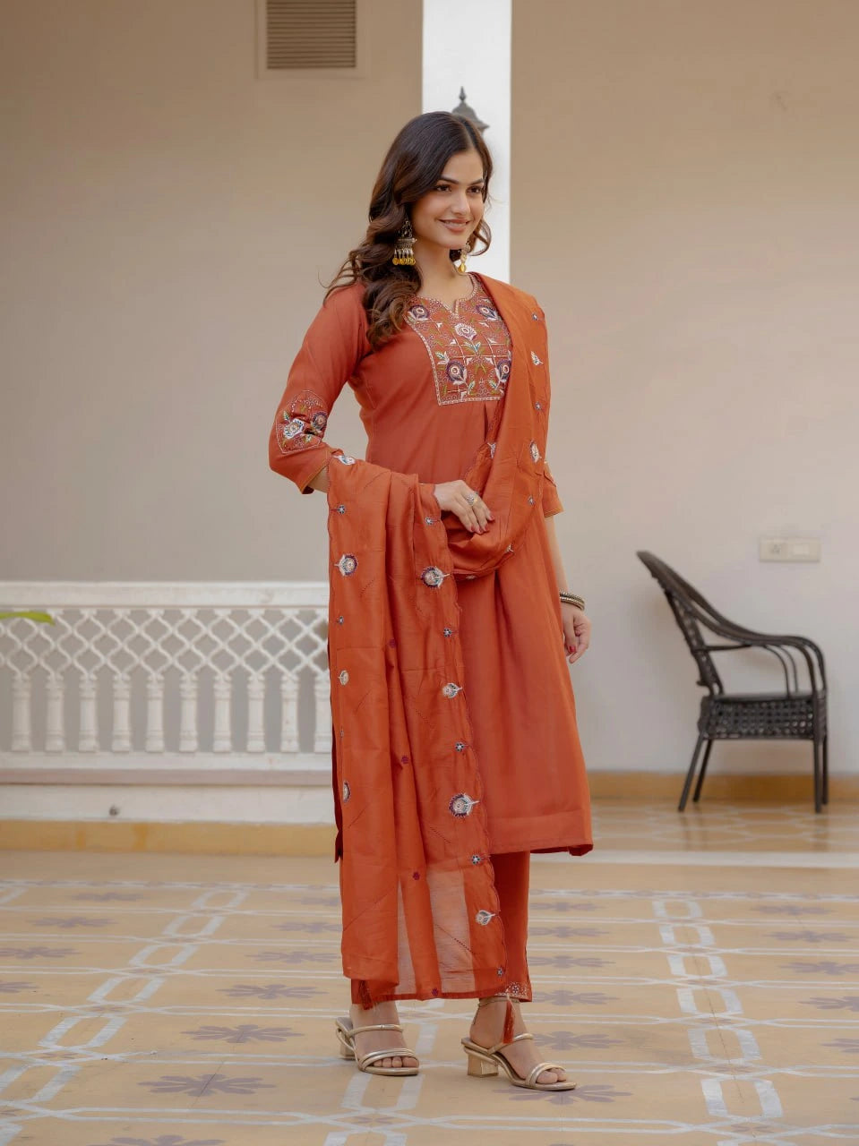 Woman wearing an orange traditional outfit with embroidery in a room.