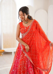 Woman wearing a bright red saree with white patterns in an indoor setting