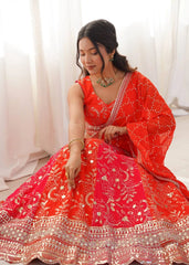 Woman in a red traditional outfit with gold embroidery sitting against a white curtain.