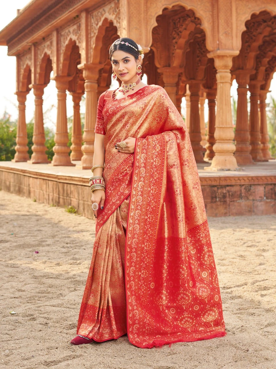 Woman in a traditional saree standing in front of architectural columns