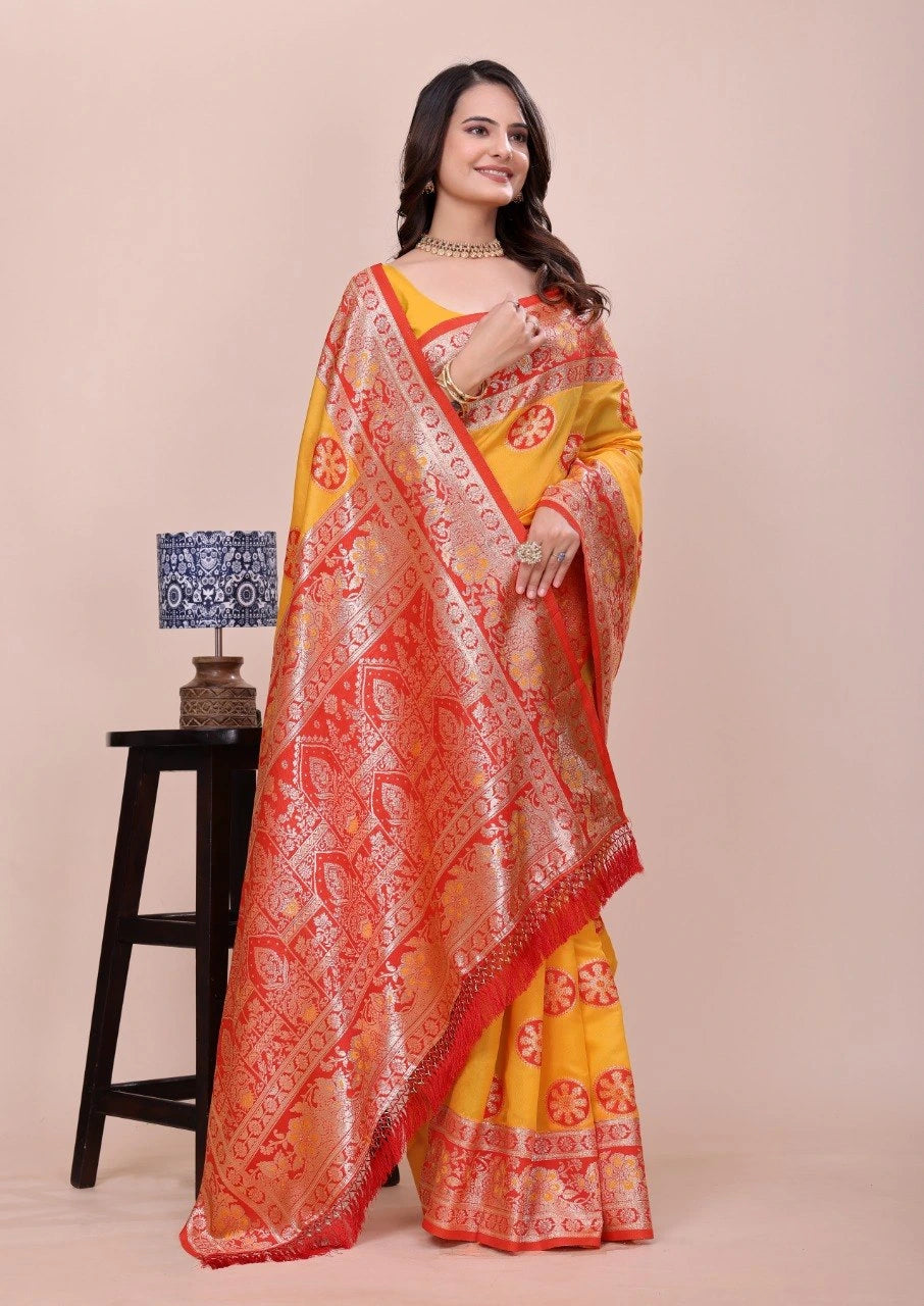 Woman wearing a yellow and orange saree with a lamp and stool in the background