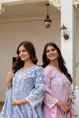 Two women in traditional embroidered dresses standing side by side outdoors.