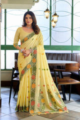 Woman wearing a yellow saree with floral patterns in an indoor setting.