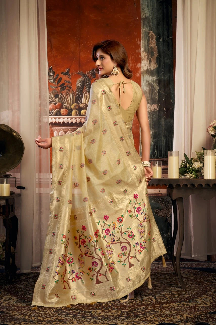 Woman in a light green saree with floral patterns standing in an elegant room.