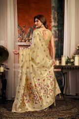 Woman in a light green saree with floral patterns standing in an elegant room.