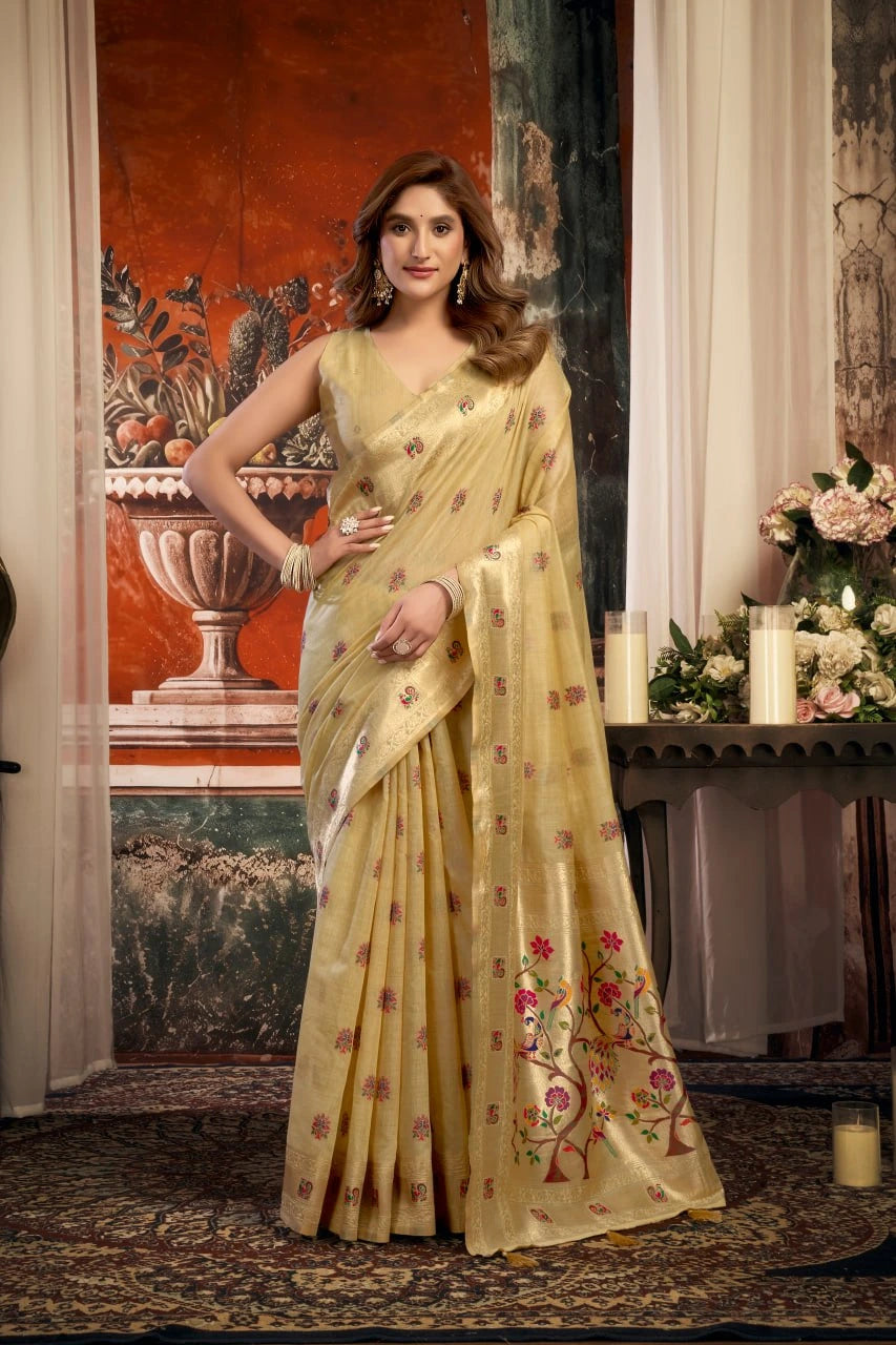 Woman in a yellow saree with floral patterns standing in an elegant room.