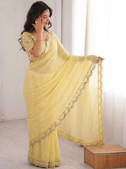 Woman wearing a yellow saree with gold border indoors.