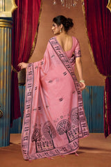 Woman wearing a pink saree with a tree design against a decorative backdrop