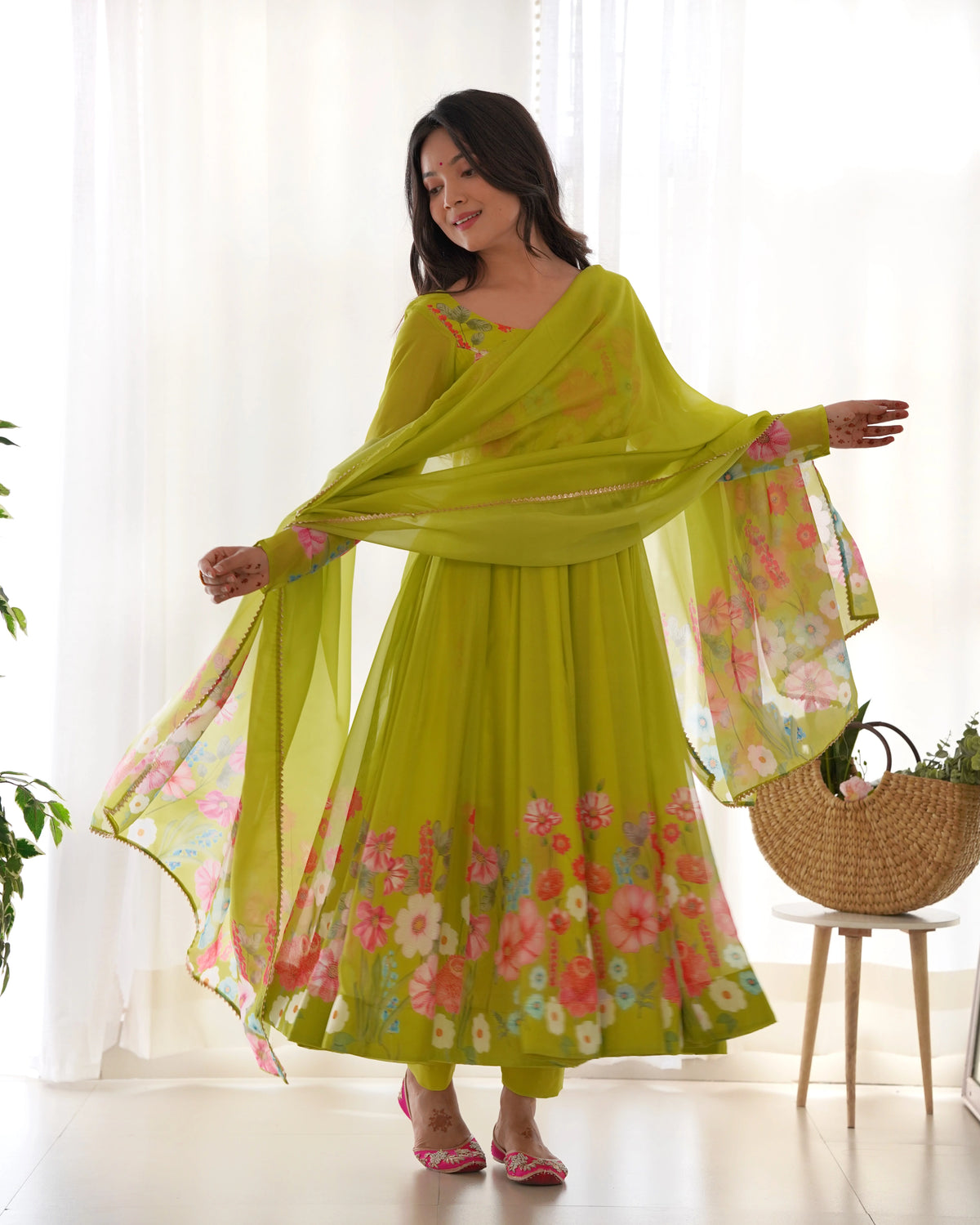 Woman wearing a green floral dress with a matching dupatta in a bright room.